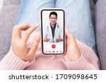 Asian chinese doctor or therapist help releave stress from coronavirus crisis video conference call online live talk remotely with woman sit on sofa couch at home using smartphone doctor consultation.