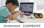 Small photo of Asia home school young small kid happy smile self study online lesson excited make AI circuit toy. STEM STEAM digital scratch class on laptop screen for active children play arduino enjoy fun hobby.