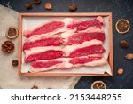 Small photo of Fresh Sliced brisket beef with rosemary on wooden plate, Sliced brisket beef on black wooden background.