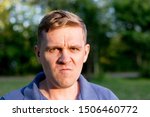 Small photo of Enraged infuriated man. Portrait of a young man on nature background. Emotion facial expression.