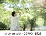 Small photo of Beautiful woman taking deep breaths, missing and stretching in a backlit park. Upper body cut with profile view from back. Copy space available on the right.