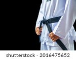 Taekwondo traditional master judo aikido man hand hold black-belt on black background for advertising. The karate man standing with black belt isolated on black with copy space.