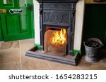 Small photo of Cambridgeshire, UK - Circa February 2020: Traditional waiting room seen at a railway station. Showing a burning coal fire to keep waiting passengers warm. Used as a public display for a bygone era.
