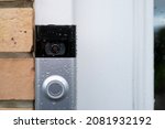 Small photo of London, UK - Circa November 2021: Close up of a Wireless Smart Doorbell send during a heavy downpour with water droplets on its surface. Seen next to a shut door.