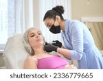 Small photo of clinical setting, cosmetic professional carefully administers filler injection into patient's jowls, part procedure aimed at contouring face and reducing masseter lines.