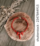 Small photo of Red natural coral stone handmade necklace on the tree log, dried herbs. Ukrainian woman traditional jewelry, handcraft, flat lay. Irregular beaded coral necklace, gemstone jewelry, accessory top view