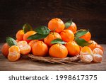 Fresh mandarin oranges fruit or tangerines with leaves on a wooden background