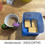 Small photo of A cozy morning tableau featuring a mug of milk coffee with a crisp of crackers, promising a simple yet satisfying breakfast.