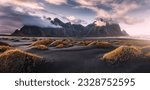 Small photo of Stunning moody dramatic landscape image with cloudy mountain in Iceland during sunset. Impressive Colorful Seascape of Iceland. Wonderful picturesque Scene near Stokksnes cape and Vestrahorn Mountain