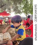 Small photo of Bengkulu 16 november 2023 A child who was eating in the prosperous city square looked like he was really enjoying his meal with great gusto