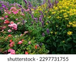 Small photo of This is a photograph of a beautiful flower garden. The garden is filled with various types and colors of flowers that are in full bloom. Some of the flowers are pink, yellow, purple.
