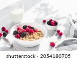 Morning healthy breakfast, white bowl full with granola, muesli, raspberry, blackberry on gray concrete table. Healthy eating, eco, bio food concept. Fresh tasty meal on grey background. Quality photo