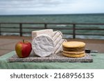 Small photo of Four famous cheeses of Normandy, squared pont l'eveque, round camembert cow cheese, yellow livarot, heartshaped neufchatel and view on promenade and ocean in Etretat, Normandy, France