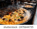 Street food in London, food court on Portobello road Saturday market, fresh prepared colorful paella with rice and sea food in big pan, ready to eat