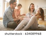 Happy family with two daughters playing at home. Family sitting on floor and playing together.