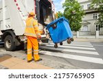 Small photo of garbage and waste removal services. Worker loading waste bin into truck at city