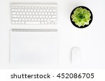 White office desk table with wireless aluminum keyboard, paper, mouse and succulent flower in pot. Top view with copy space. Flat lay.