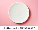 Round white plate on pink background, top view