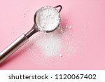 Strainer with powder sugar on pink background, top view