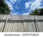Old wooden fence in the backyard and flowing white clouds with blue sky and a corner of green trees, family lifestyle.