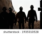 Silhouette of miners with headlamps entering a mine