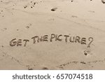 Small photo of Handwriting words "GET THE PICTURE?" on sand of beach.