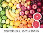 Fresh ripe colorful organic fruits from market: apple and orange, grapefruit and banana, grape and berries; rainbow colors fruit background