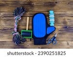 Small photo of Pet slicker brushes, claw clipper and toys on wooden background. Top view