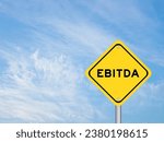 Small photo of Yellow transportation sign with word EBITDA (abbreviation of earnings before interest, taxes, depreciation and amortization) on blue color sky background