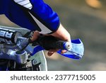 Small photo of Close up detail image man riding dirt bike. Hand on throttle. Braaap. Blue. Blurred background. Recreation. Leisure. Activity. Riding. Outdoors. Trail. Dirtbike.