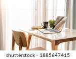 Beautiful workspace - online remote work from home concept. A wooden table with computer laptop, smartphone, coffee cup beside the window balcony with sun light shine through the curtain. No people.