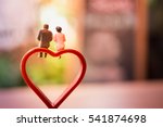 Miniature of a women and a man in love sitting on heart sign bench with bokeh light copyspace, couple in love and pre-wedding background concept