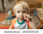 Small photo of Portrait of a blond-haired, blue-eyed, curious and impish toddler.