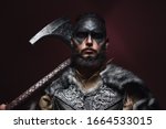 Small photo of portrait of a Viking man with an axe. A man of 30 years holds a large battle axe on his shoulder. Warrior dressed in an authentic suit