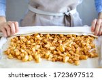 Hands wrap the dough with apple filling make apple strudel.Girl is preparing a pie at home in an apron.Work with puff pastry.The process of making apple strudel.Mom makes a pie.Apple strudel roll