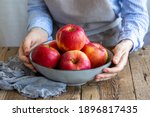 Small photo of Apple saved. Apples washed in a bowl in the hands of the girl. A plate with red apples on a wooden table. Cooking food. Vegan. Food for vegetarians and vegans. Fresh fruits. Vitamins. Proper nutrition