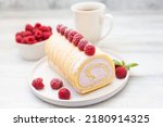 Small photo of Tasty roll cake, sponge roll, Swiss roll stuffed with cream cheese ,decorated with fresh raspberries.