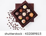 handmade chocolates in a square box and coffee beans near (top view)