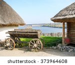 An old Ukrainian carriage, traditional huts and a view of the Dnieper Hydroelectric Station ("DniproHES") from the historical complex "Zaporizhian Sich" on the island of Khortytsia by summer.