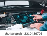 Mechanic working close to an automobile engine while using a laptop. A screen-based automotive diagnostic application. idea of a car service