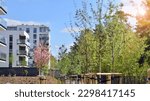 Small photo of Ecology and green living in city, urban environment concept. Modern apartment building and green trees. Ecological housing architecture. A modern residential building in the vicinity of trees.