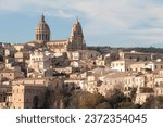 Small photo of ragusa sicily italy town medium shot church buildings homes houses on hill unlevel uneven ground with sky above