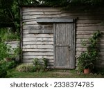 A old wooden shed, in the middle of a lovely garden, with a sign that means 