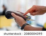 Small photo of Cashier holding credit card reader machine on hand with insert card for payment process from customer, pressing the value number or price of products to charge the online payout, online deduction