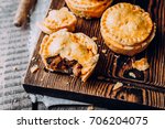 Fresh Traditional Australian meat mini pie on the wooden board on table background, closeup with copy space, top view, rustic style