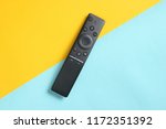 A modern TV remote control on pastel background. Top view, minimalism