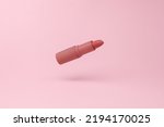 Small photo of Red lipstick tube flying in antigravity on pink background with shadow. Levitation object in the air. Beauty and fashion concept. Creative minimal layout