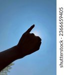 Small photo of Pinkie finger, pinky promise silhouette on blue sky background with sun.