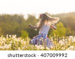 Girl running on the field of dandelions on summer sunset. Beautiful little kid girl  dancing on dandelion meadow with sunset. Summer fun outdoors.
