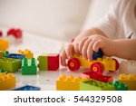 Close up of child's hands playing with colorful plastic bricks at the table. Toddler having fun and building out of bright constructor bricks. Early learning.  stripe background. Developing toys